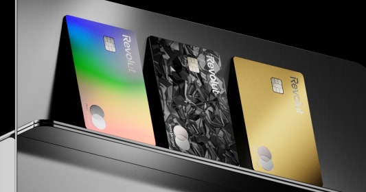 Trois cartes bancaires Revolut colorées, noire et dorée.