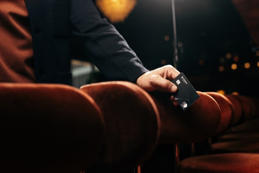 Homme tenant une carte bancaire noire dans un fauteuil.