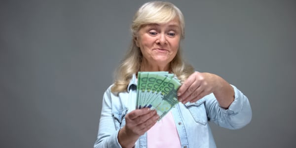 Femme senior joyeuse comptant des billets en euros