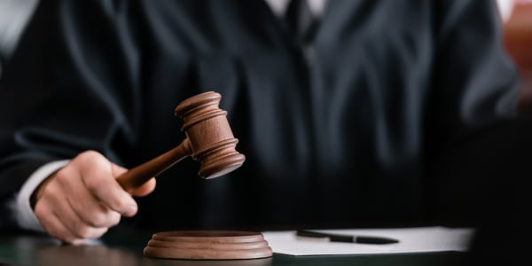 vue partielle du juge flou en robe tenant un marteau dans un tribunal