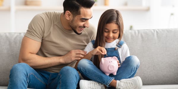 Petite fille et papa �conomisant de l'argent dans une tirelire