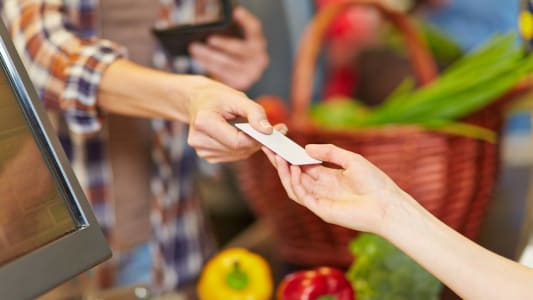 Femme prsentant sa carte bancaire  la caisse d'un supermarch