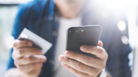 Jeune homme tenant un iPhone et une carte bancaire