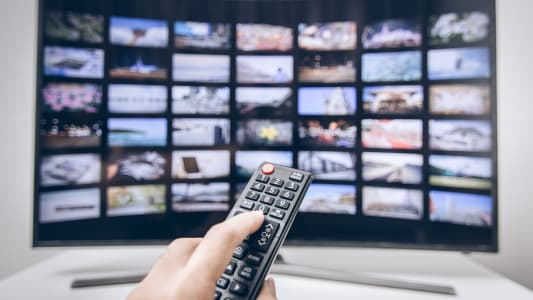 Une main presse les boutons de la tlcommande d'une smart TV