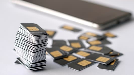Pile de cartes SIM avec smartphone en arrire-plan