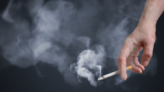Main d'un homme tenant une cigarette allume