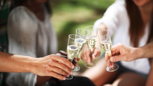 Personnes en train de trinquer avec des verres de vin ptillant