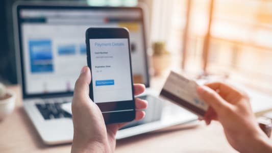 Homme utilisant sa banque en ligne sur smartphone et ordinateur 