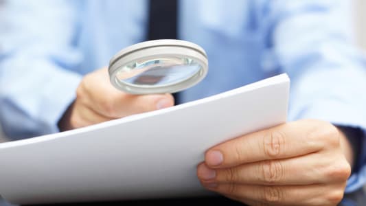 Un homme en costume lit un document avec une loupe
