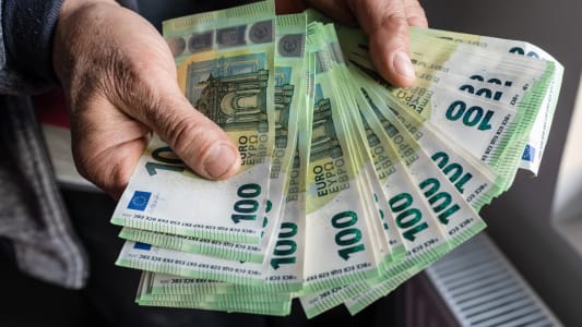Quelqu'un tient plusieurs billets de 100 euros.