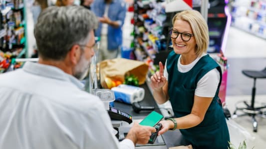 Une caissire fait payer un client dans un magasin.