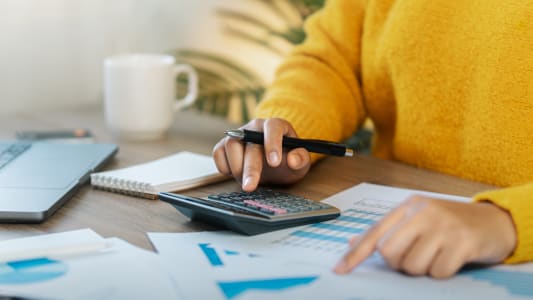Une personne tient une calculatrice et regarde des documents.
