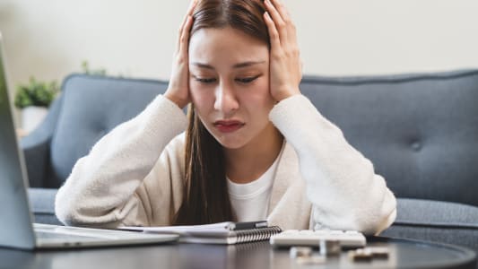 Une femme se prend la tte dans les mains en regardant des documents.