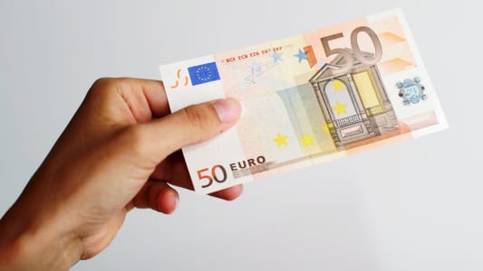 Quelqu'un tient un billet de 50 euros.